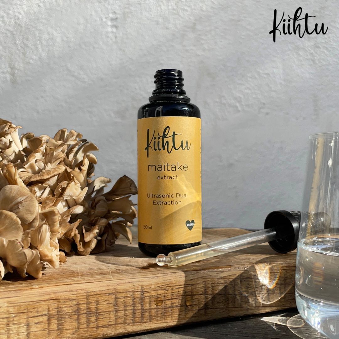 Kiihtu Maitake Mushroom Extract bottle placed next to raw Maitake Mushrooms and shown simply being added to a glass of water