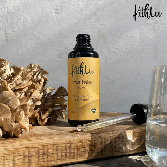 Kiihtu Maitake Mushroom Extract bottle placed next to raw Maitake Mushrooms and shown simply being added to a glass of water