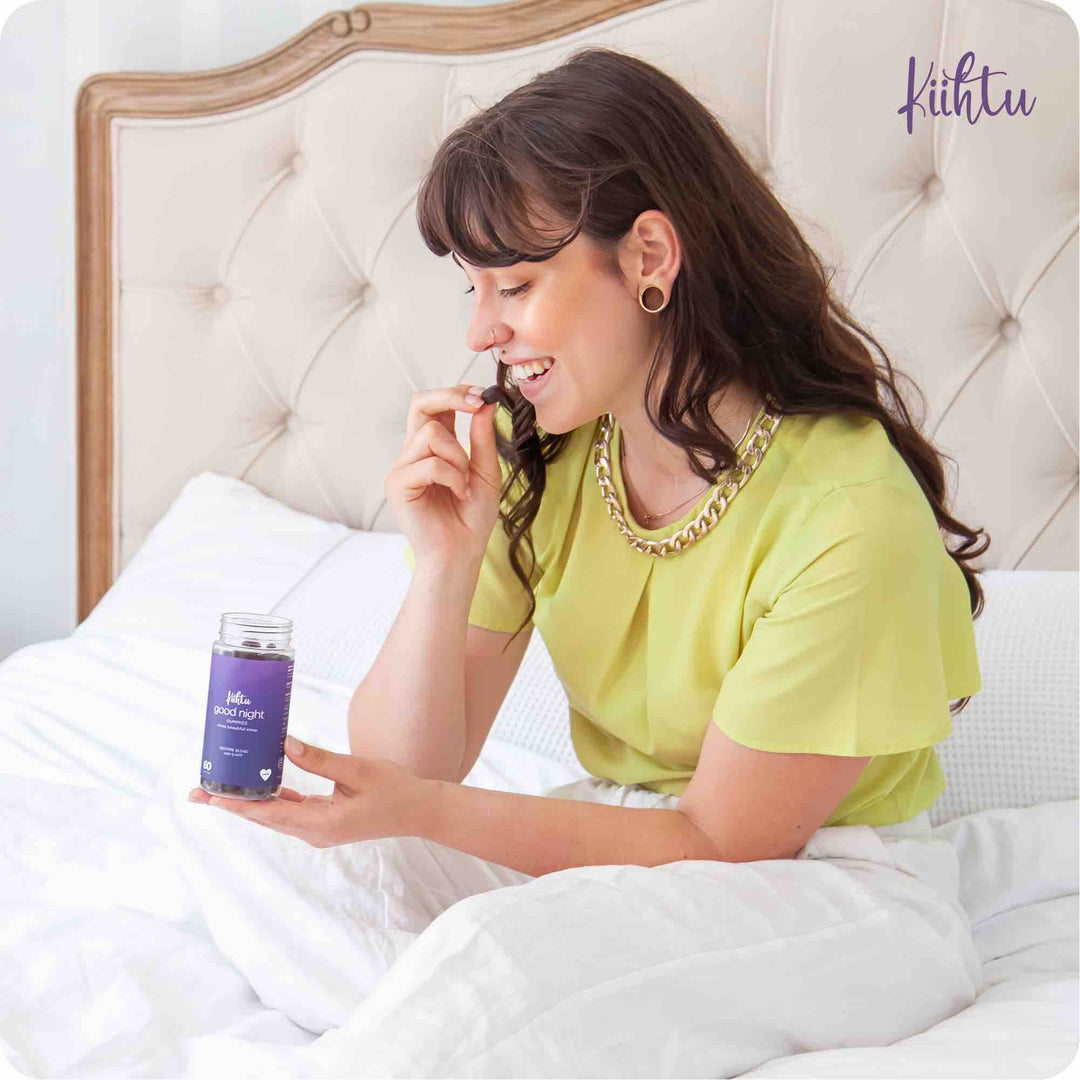 A woman sitting in bed holding Good Night Gummies by Kiihtu